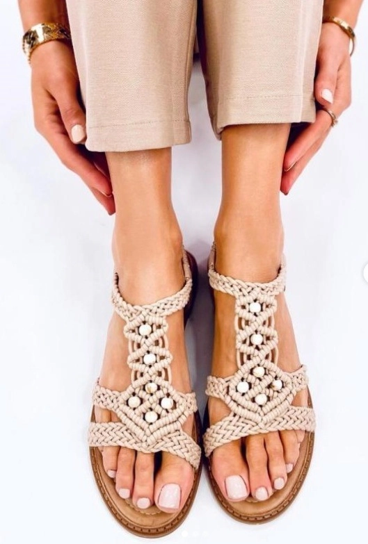 A nő divatos bézs szandált és arany ékszereket visel