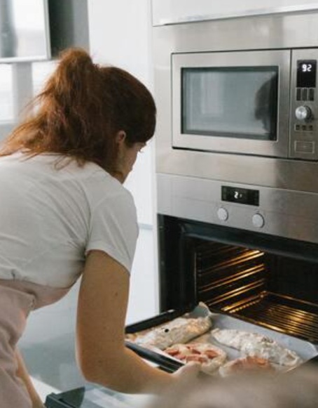 A nő egy tepsit tesz be a sütőbe