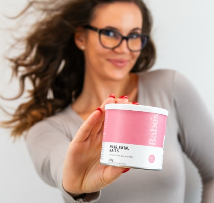 A nő Babes Vitamins kollagén terméket tart a kezében