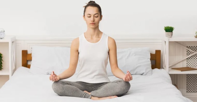 a nő az ágyon ül és meditál