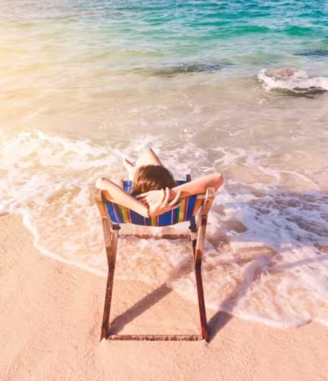 A nő a tengerparton ül strandszékben