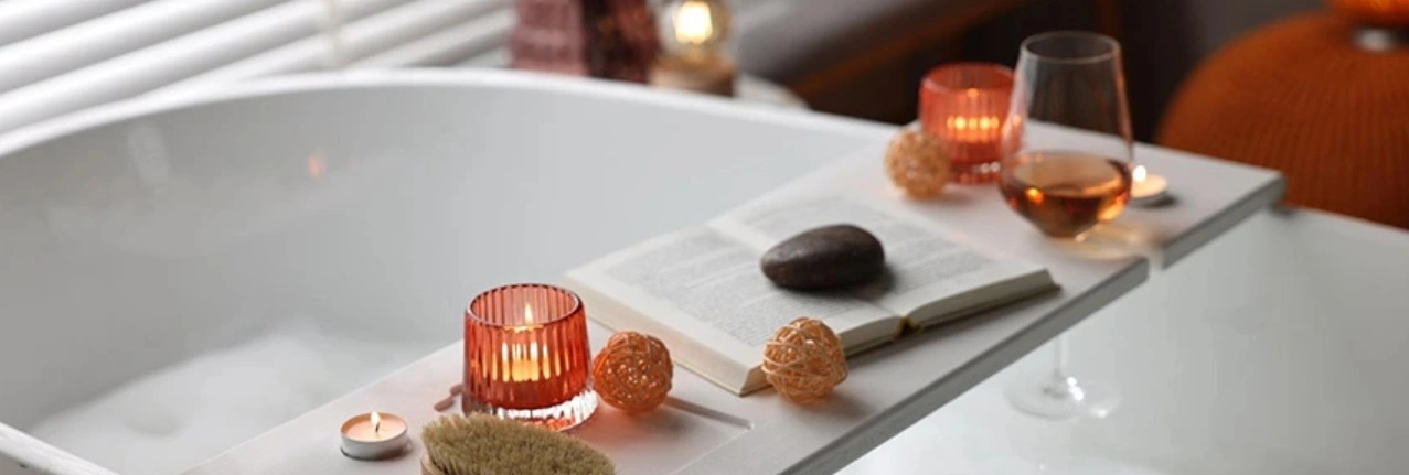 Otthoni wellness a fürdőszobában illatgyertyákkal és egy pohár borral