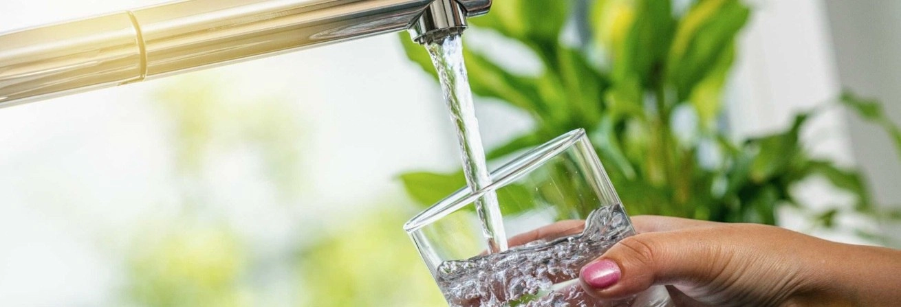 A csapról tiszta víz folyik egy pohárba