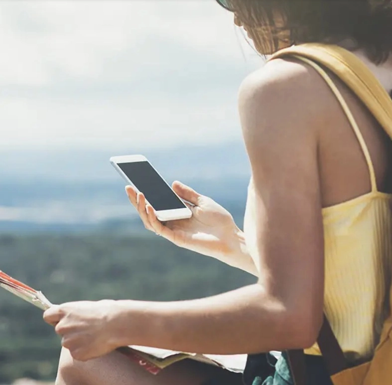 A nő a térképet és a telefonját nézi