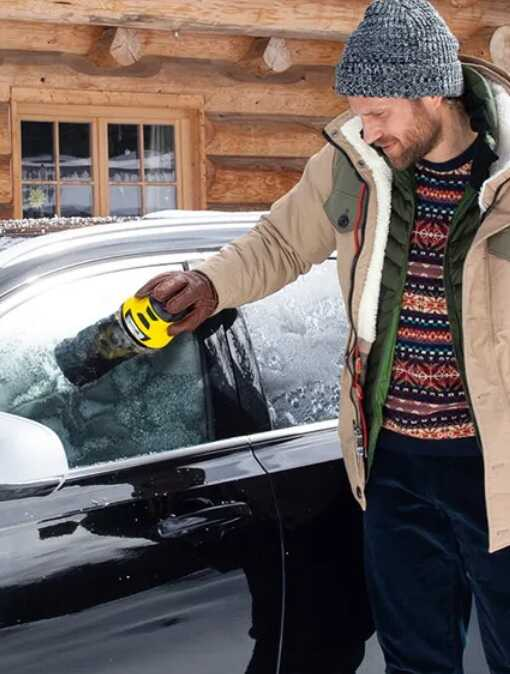 A férfi karcher géppel olvasztja le a jeget a kocsija ablakáról