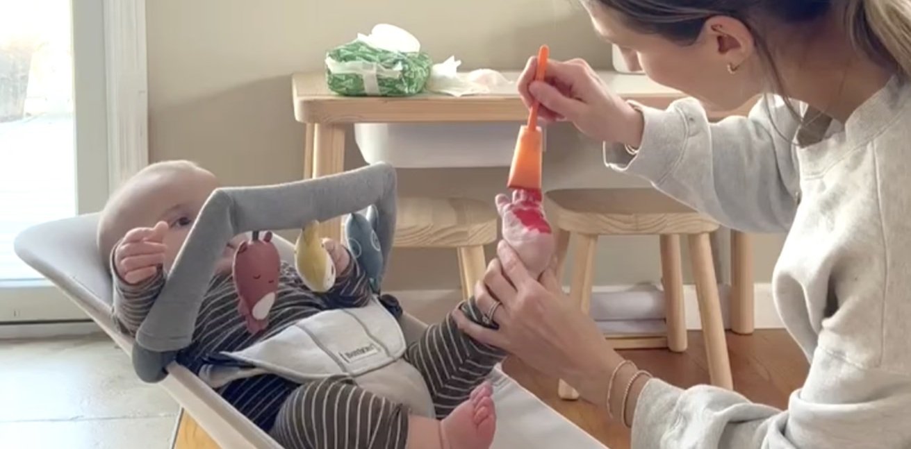 A baba a hintaszékben, miközben az anyja a lábát festi