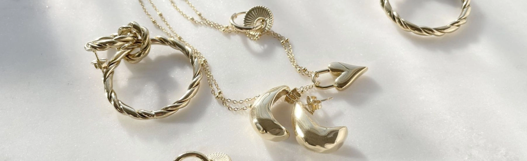 Arany nyaklánc, fülbevaló és gyűrű fehér alapon