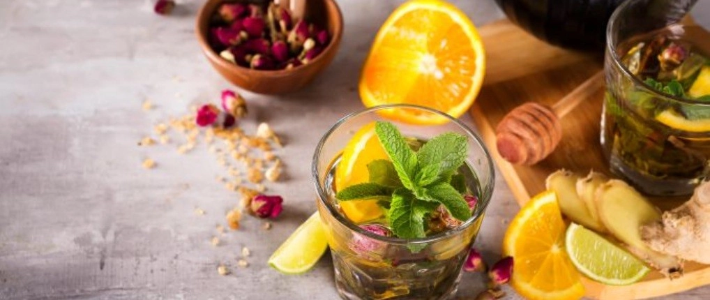 Gyógynövényes te, amely körül gyümölcsök hevernek az asztalon