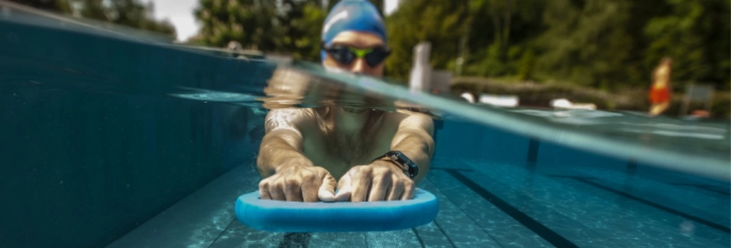 A férfi a medencében úszik