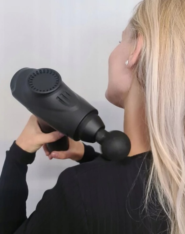 Nő masszázspizstolyt használ