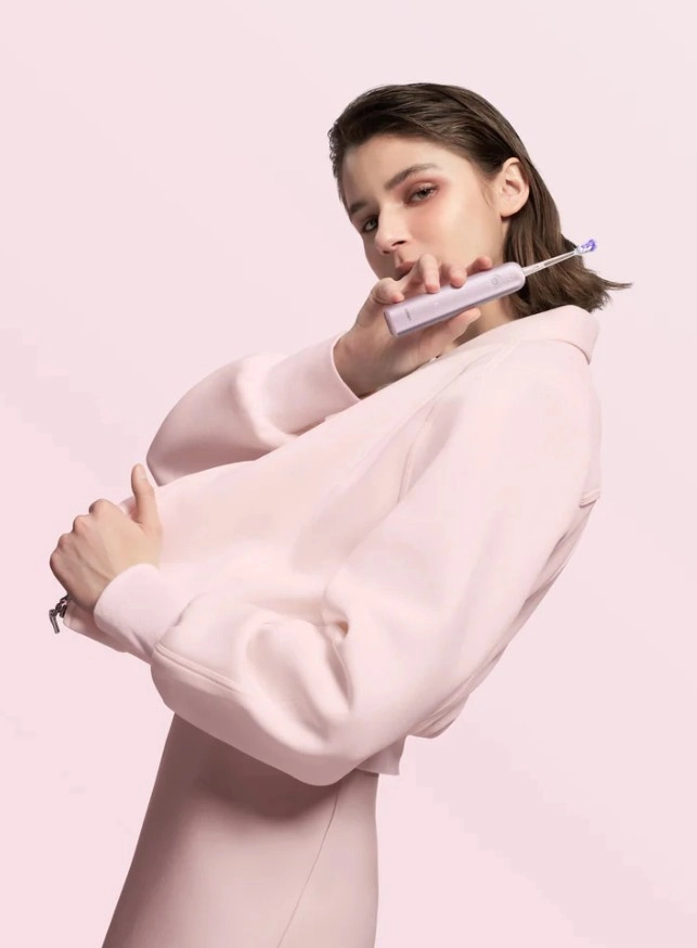 Egy barna hajú nő, fogkefét tart a kezében